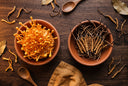 Cordyceps militaris orange et cordyceps sinensis séché côte à côte sur bois
